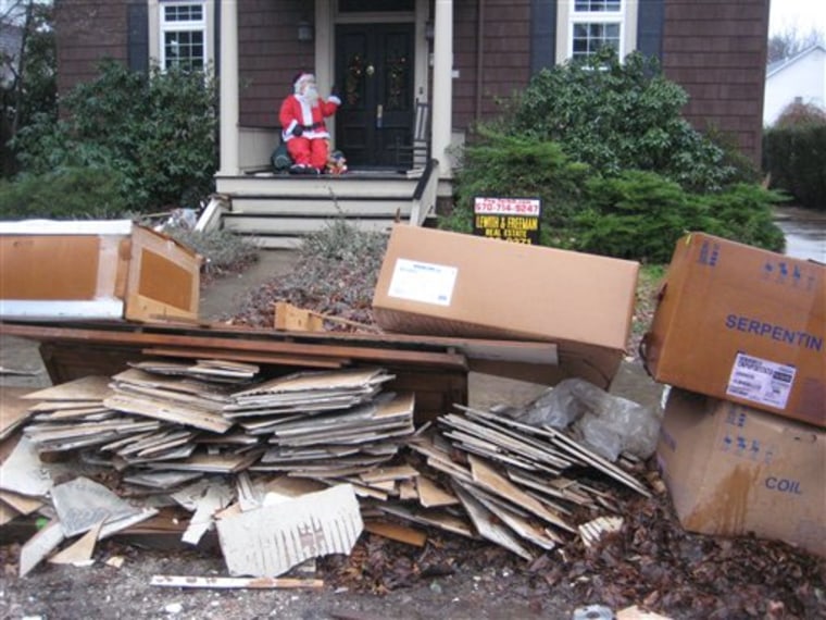 In this Dec. 21, 2011 photo, flood debris awaits pickup as a Santa Claus is seen on the porch of a home in West Pittston, Pa. More than three months after Tropical Storm Lee flooded towns up and down the Susquehanna River, many residents are frustrated by the slow pace of recovery and will be out of their homes for Christmas. (AP Photo/Michael Rubinkam)